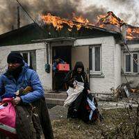 Família retira pertences de casa bombardeada em Irpin, nos arredores de Kiev, nessa sexta-feira