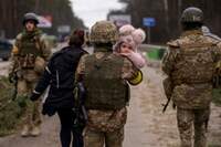 Soldado ucraniano carrega criança no colo enquanto ajuda família em fuga a atravessar o rio Irpin, nos arredores de Kiev, capital da Ucrânia