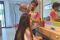 Preparativos no salão de beleza infantil com direito a penteado nos longos cabelos e uma delicada maquiagem