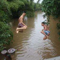 Jovens se divertem e nadam no canal da capital em mais um dia de chuva e maré alta.