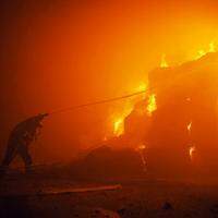 Socorrista tenta apagar incêndio em um prédio após a queda de destroços, durante um ataque massivo de drones visando principalmente a capital ucraniana