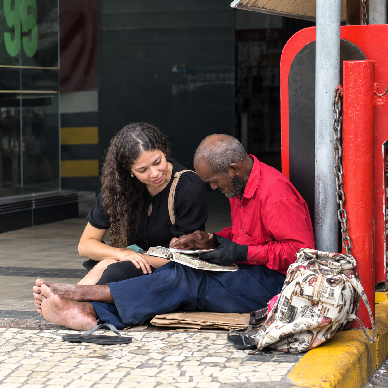 Jovem sentou no chão ao lado do idoso para ler algo para ele