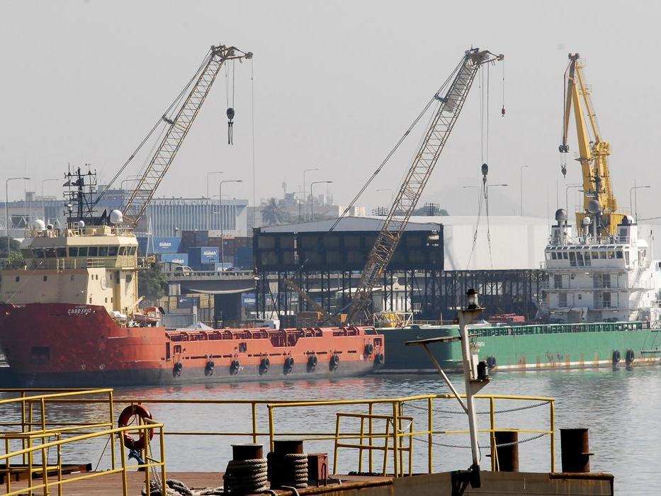 A imagem mostra navios atracados no Porto do Rio de Janeiro, com guindastes e embarcações de apoio de fundo